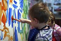 Zwei Kinder bemalen eine Wand mit bunten Farben.