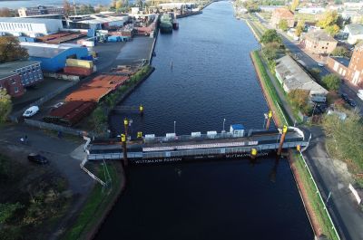 Luftbildaufnahme des Kanalbereiches westlich der Deichbrücke. Über den Kanal verläuft ein Schwimmponton mit einer Fahrbahn.