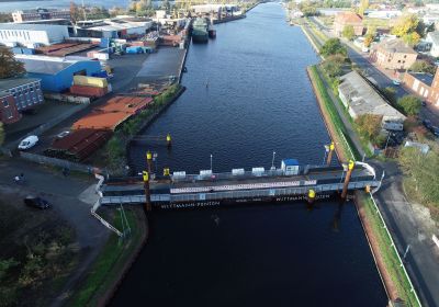 Luftbildaufnahme des Kanalbereiches westlich der Deichbrücke. Über den Kanal verläuft ein Schwimmponton mit einer Fahrbahn.