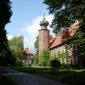 Burg Kniphausen mit Zwiebelturm umgeben vom Grün der Parkanlage an einem sonnigen Tag.