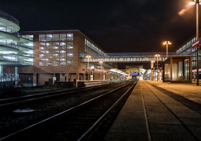 Der Bahnhof Wilhelmshaven bei Nacht, aufgenommen entlang der Bahnsteigkante und umgeben von den Lichtern der Nordseepassage.