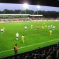 Ein Fußballspiel unter Flutlicht im Jadestadion. Im Vordergrund sind die Köpfe der Zuschauer auf der vollbesetzten Tribüne zu sehen.